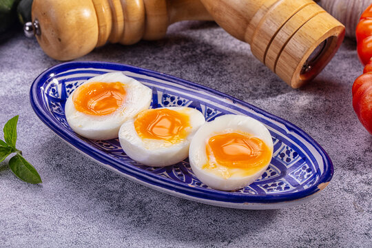 Soft boiled eggs with runny yolk served on blue patterned plate for breakfast
