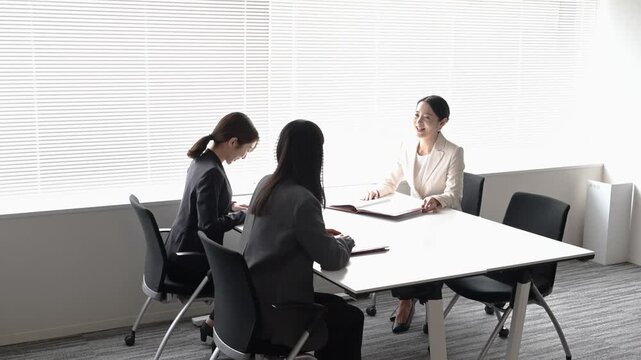 会議室で歩きながら打ち合わせを行う20代から40代の日本人ビジネスパーソン3人