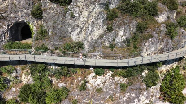 Woman Cycling on Ciclopista del Garda Cliffside Bike Path near Rock Tunnel, Limone sul Garda, Italy