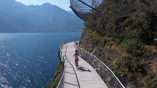Woman Cycling on Suspended Lake Garda Bike Path Below Rocky Cliffs, Limone sul Garda, Italy