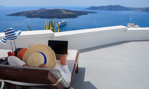 Digital nomad man working on laptop computer while relaxing in Santorini Greece, remote work and summer vacation concept