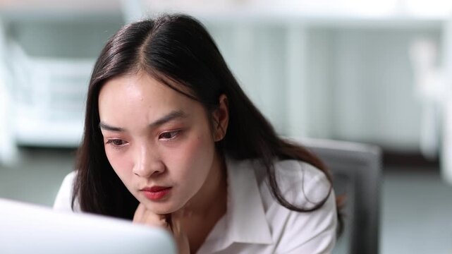 Businesswoman getting a headache working on computer. Stress and pressure from deadlines contribute to her frustration and fatigue.