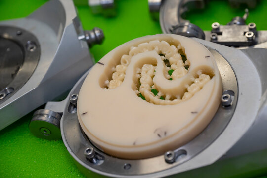 Close-up of artificial teeth and dental restorations being manufactured from a ceramic disc using precision CAD CAM equipment in a modern dental laboratory.