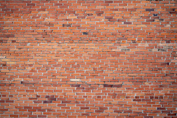 Naklejka premium Textured red brick wall with varying shades and patterns, ideal for backgrounds and design projects