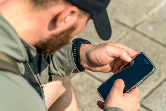 Bearded man in a black cap using his smartphone