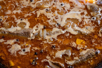 Fototapeta premium Close-up of simmering beef stew with spices and vegetables in a pot on the stove
