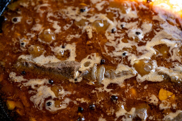 Fototapeta premium Close-up of simmering beef stew with spices and vegetables in a pot on the stove