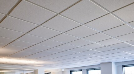 Fototapeta premium Close-up of acoustic ceiling tiles in a modern office with a clean grid pattern and soft ambient lighting