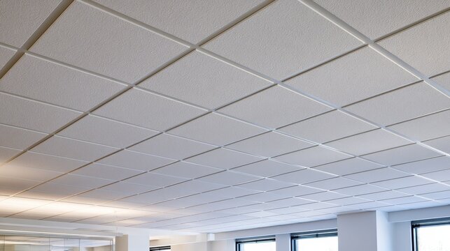 Close-up of acoustic ceiling tiles in a modern office with a clean grid pattern and soft ambient lighting