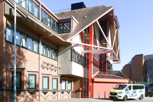 Exterior view of the Metropolitan Police Hillingdon Borough Headquarters in Uxbridge, West London, featuring contemporary civic architecture with a marked police vehicle parked outside on a clear sunn