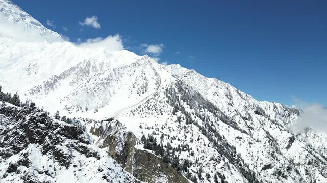 Bright daylight drone flight highlighting the massive snowy ridges and deep ice crevasses of Rakaposhi Mountain in Pakistan