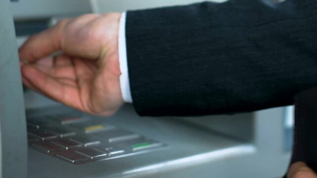 Man entering personal pin code on ATM machine keyboard and receiving american dollar bills to count money in 4K Ultra HD footage
