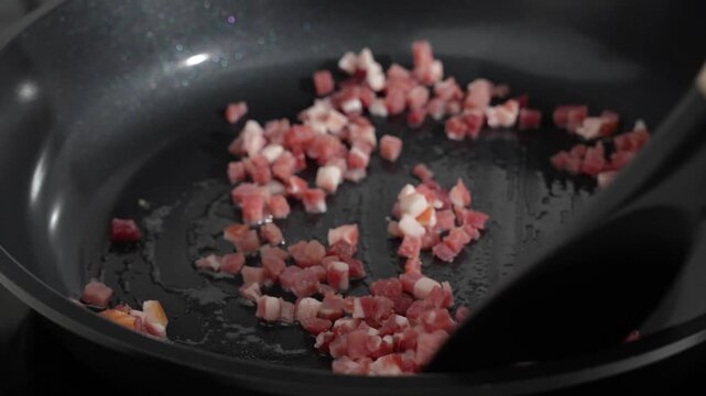 Pouring Diced Bacon into a Dark Skillet