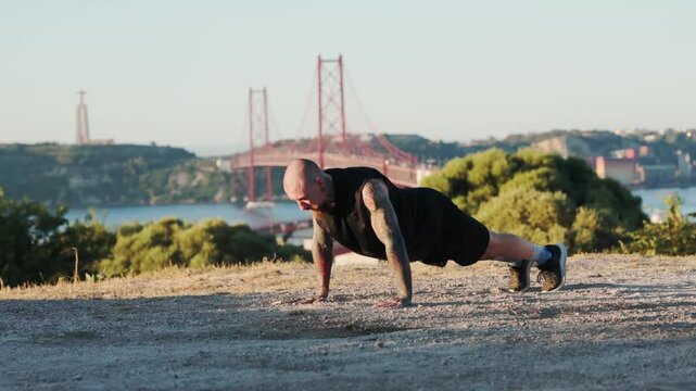 Tattooed man doing push-ups outdoors in lisbon