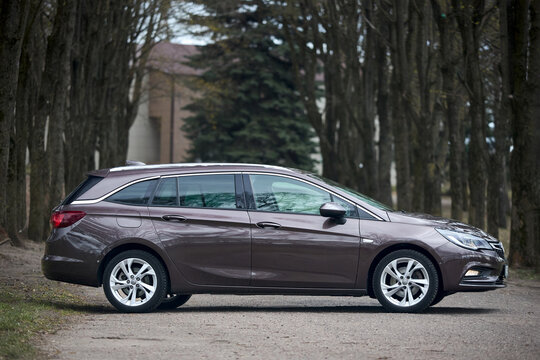 Berlin, Germany - April, 8 2026: brown opel astra sports tourer wagon parked profile view outdoor forest background transport automobile vehicle travel drive luxury family sleek modern automotive side