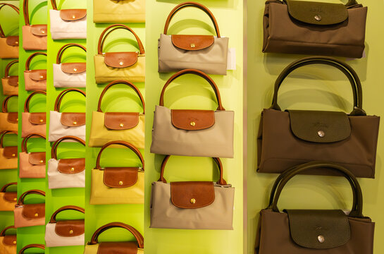 Paris, France - July 5, 2026: Colorful rows of iconic Longchamp Le Pliage folded nylon tote bags hanging on a bright green boutique display wall