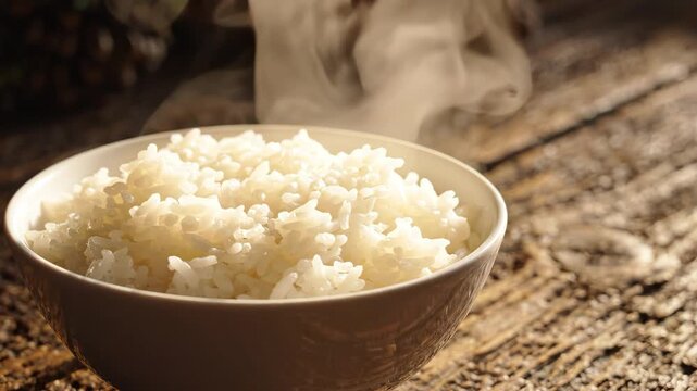 Steaming hot white rice in a ceramic bowl on rustic wooden table, close-up with rising steam