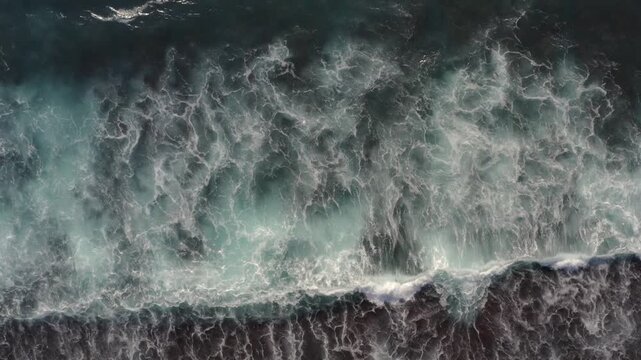 Top down aerial drone view of ocean waves crashing onto tropical beach