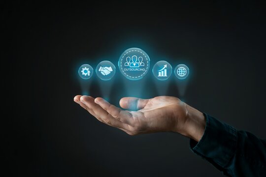 Person's outstretched hand displays a glowing array of icons centered around the word 'outsourcing'.