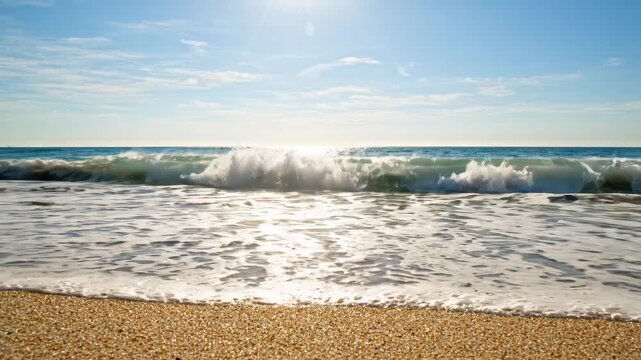 Gentle ocean waves rolling onto golden sandy beach under bright sun and clear blue sky