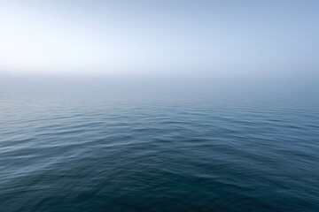 Obraz premium Glassy blue sea under a foggy horizon in tranquil seascape