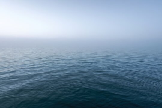 Glassy blue sea under a foggy horizon in tranquil seascape