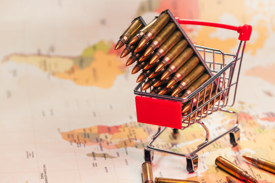 Shopping cart with rifle bullets on world map war business concept.