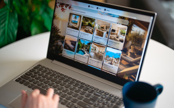 Woman browsing apartment catalog on laptop booking site.