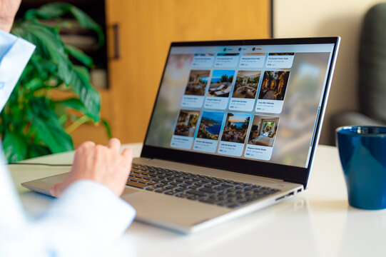 Woman browsing apartment catalog on laptop booking site.