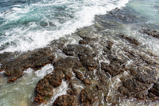 Waves breaking against dark rocks in the sea