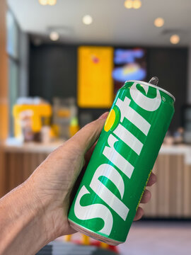 Sprite Can in hand close up. Customer Holding Open Sprite Can Inside McDonalds Restaurant with the service counter and menu boards blurred in the background