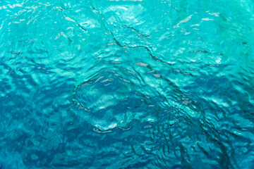 Vibrant turquoise water ripples texture background, looking down into a clear swimming pool or sea with light reflections and movement. Ideal for summer or travel concepts. © IgnasiusIMade