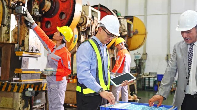 Engineers collaborating in a manufacturing facility discussing plans and project progress with safety gear