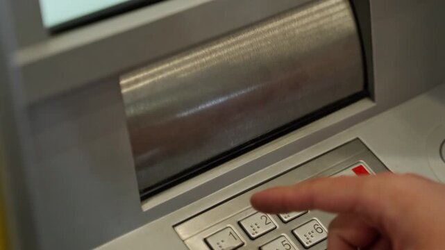 Close up of a mans hand putting a wad of cash paper money into the receiving slot of an ATM machine for automated replenishment and deposit transaction in 4K Ultra HD footage
