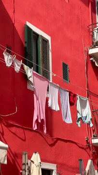 Colorful house facade with clothes hanging out to dry on a laundry line in a traditional Italian town, authentic lifestyle.