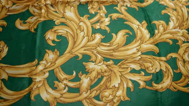 Green Silk Scarf with Gold Baroque Pattern Flowing in Slow Motion on White Background