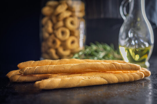 Golden Breadsticks With Olive Oil and Rosemary on Dark Table for Rustic Italian Snack