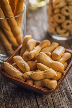 Rustic Breadsticks And Bite-Sized Savory Snacks In Wooden Bowl On Weathered Table