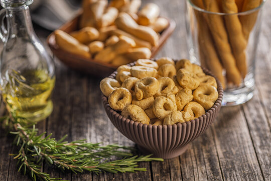 Rustic Italian Taralli Snack Bowl With Breadsticks Olive Oil and Fresh Rosemary on Wooden Table