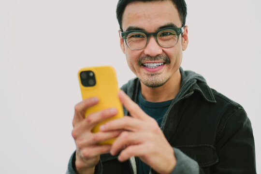 dult asian man using mobile, cell phone.portrait young male person posing smart phone smiling laughing look fun excited surprised happy.empty space for text advertising