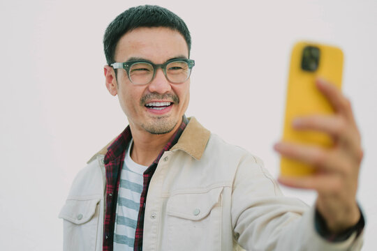 dult asian man using mobile, cell phone.portrait young male person posing smart phone smiling laughing look fun excited surprised happy.empty space for text advertising