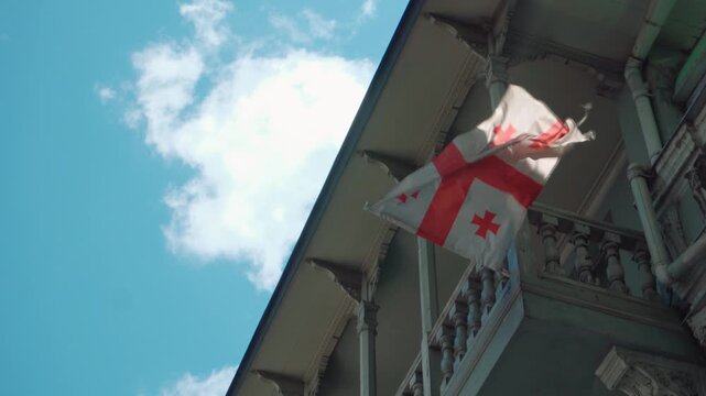 Georgian flag waving from a traditional wooden balcony in Tbilisi