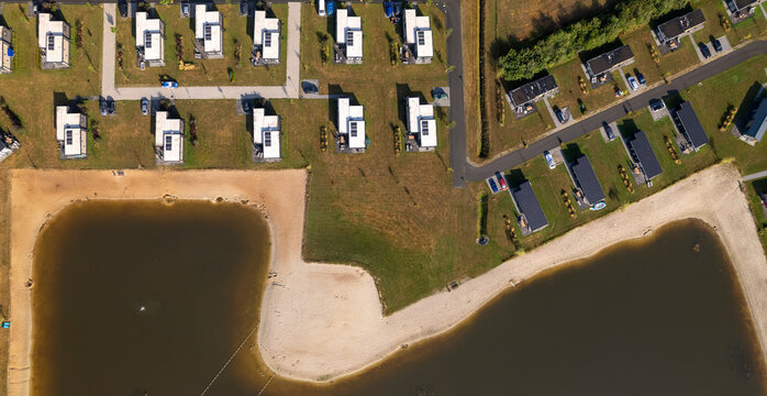 Top down aerial panorama of recreational Hoge Hexel bungalow park with summer homes around a pond with beach side access in Dutch agricultural countryside landscape vacation houses