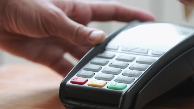 Unrecognizable person using credit card on modern wireless reader terminal for secure retail shopping transaction in 4K Ultra HD footage
