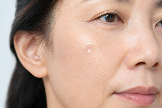Mature East Asian skin with pink PDRN inspired serum droplet