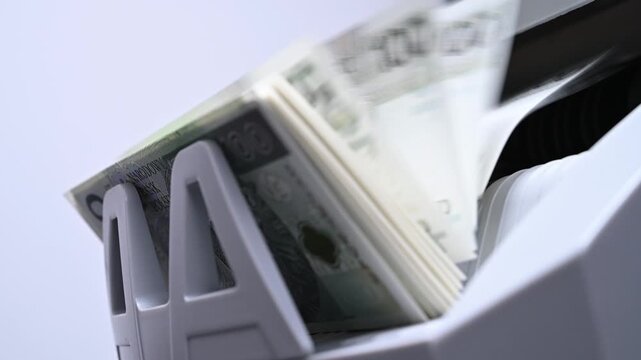 Banknote counter machine with stack of cash bills sorting rapidly for automated banking industry and financial wealth accounting in 4K Ultra HD footage
