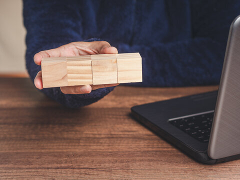 Person Holding Blank Wooden Blocks Beside Laptop
