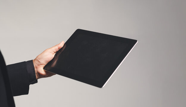 Hand Holding Tablet with Blank Screen on Gray Background