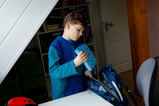 School kid boy getting ready in the morning for school. Healthy child filling satchel with books, pens, folders and school stuff. Preaparation, routine concept.