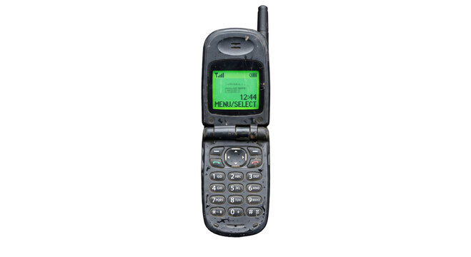 Old flip phone covered in dirt and grime, showing a green screen display